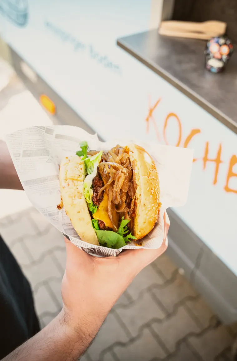ein kunde von foodliner foodtruck hält einen burger in der hand